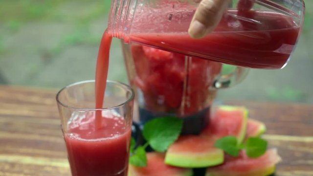 pouring  watermelon Juice into glass  and blender  with chunks of  fresh watermelon 
