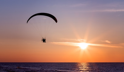 Paraglider flying at sunset