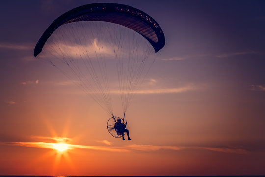 Paraglider flying at sunset