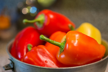 Sweet red peppers in colander on wooden background