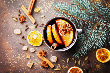 Mug of christmas mulled wine or gluhwein with spices and orange slices on rustic table top view....