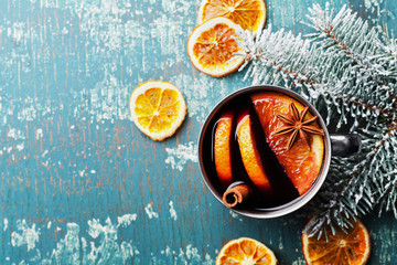 Hot christmas mulled wine or gluhwein with spices and orange slices on vintage teal table top view. Traditional drink on winter holiday.