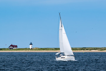 Fototapeta premium Sailboat with Lighthouse in the background