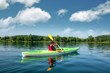 Boy in life jacket on green kayak - obrazy, fototapety, plakaty