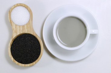 Water the Back Sesame in a white cup and Back Sesame,white sugar in a wood spoon.
