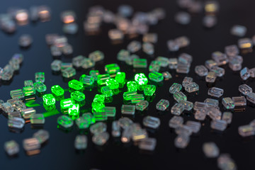 Transparent glass beads on black background illuminated by green laser