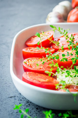 Tomato slices in a baking dish with herbs and spices. Selective focus, copy space.