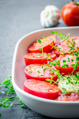 Tomatoes in a baking dish with garlic and thyme. Close up, selective focus.