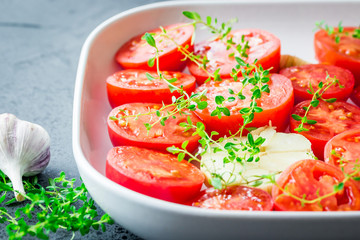 Tomato slices in a baking dish with garlic and thyme. 