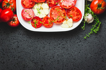 Tomato slices in a baking dish with spice s and herbs. Top view, space for text.