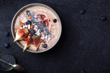 Blueberry banana smoothie bowl with figs and coconut. Dark food photography concept. Flatlay with copy space