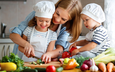 Healthy eating. Happy family mother and children  prepares   vegetable salad in kitchen.