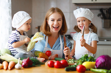 Healthy eating. Happy family mother and children  prepares   vegetable salad in kitchen.