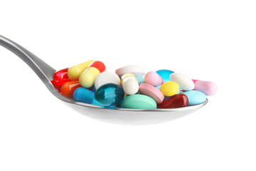 Spoon with colorful pills on white background