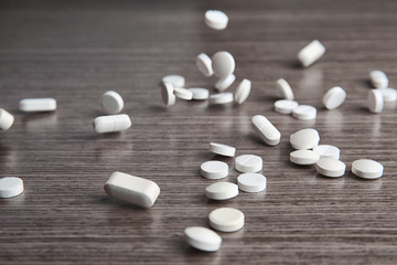 Fototapeta na wymiar Scattering white pills on wooden table