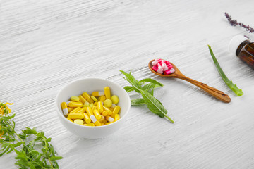 Colorful pills and herbs on wooden background