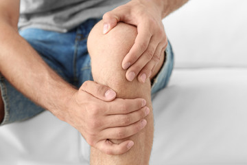 Young man suffering from leg pain at home