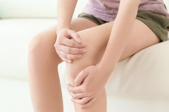 Young woman suffering from leg pain at home