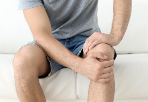 Young man suffering from leg pain at home