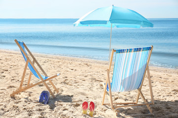 Fototapeta na wymiar Beach chairs and umbrella on sea coast