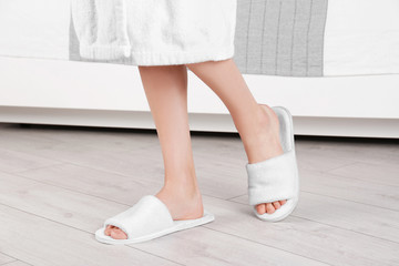 Woman standing in white spa slippers on grey parquet