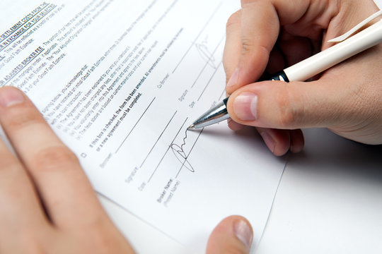 the man's hand signs the document and the signature
