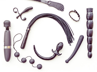 Different sex toys are arranged diagonally on a light background. There is free space for your text