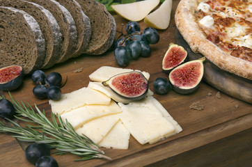 Pizza on board, cheese, bread and rosemary