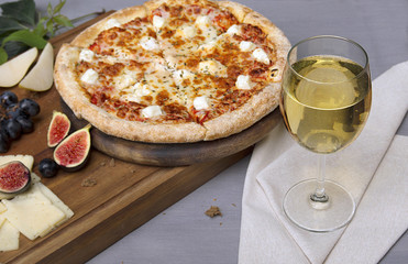 Pizza on board, cheese, bread and glass of wine