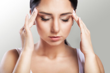 Pain. A beautiful woman on a gray background, stress and headache with migraine headaches, she wrestled with pain, a big portrait, high quality, professional makeup.