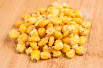 Pile of roasted spiced corn kernels on a wood background