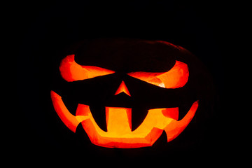 A very terrible Halloween pumpkin, with a terrible look and a smirk of a villain, in the dark