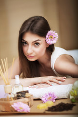 Obraz na płótnie Canvas Spa treatments. Beautiful young girl lying on a massage table. Aroma oil.Clean and well-groomed skin. Beautiful smile. Conception of beauty and health.
