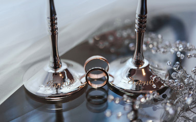 золотые обручальные кольца и свадебные аксессуары на стеклянном фоне © oes