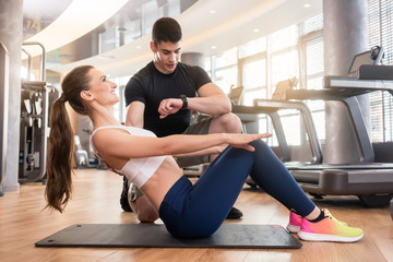 Junge Frau beim Fitness Training im Gym mit Lehrer macht Core Übungen
