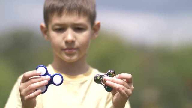 Happy Boy holding play two fidget spinners on nature close up