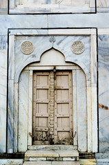 Old mughal architecture wooden door set in a beautiful archway in a marble wall
