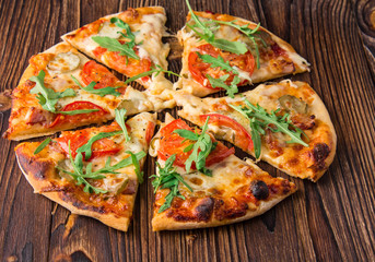 Homemade pizza with tomatoes, cheese, meat and herbs. Pizza on a wooden background. Restaurant meal. Copy space.