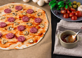 Raw pizza with ingredients.