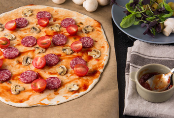 Raw pizza with ingredients.
