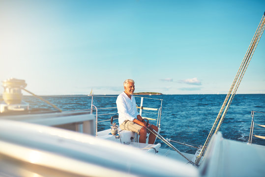 Smiling mature man sitting on the deck of his sailboat