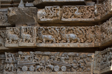Mysore, India - October 27, 2013: Close up of three brownish stone friezes on outside wall of central shrine, called Trikuta, at Chennakesave temple in somanathpur. LInes of ducks, monsters, war scene