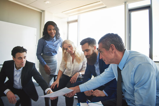 Diverse Work Collegues Discussing Paperwork Together In An Office