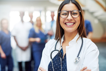 Smiling young doctor standing in front of medic team