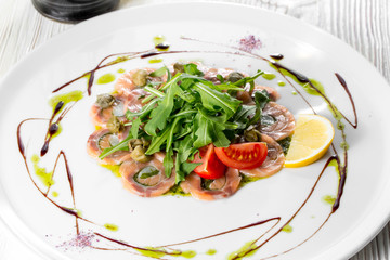 Salmon carpaccio with arugula leaves and sticky balsamic vinegar