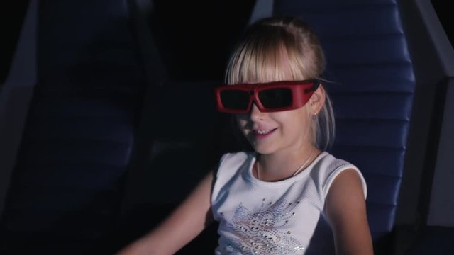 Cool blonde girl in 3d glasses watching a movie at the cinema. It blows the wind, the dynamic moving Chair