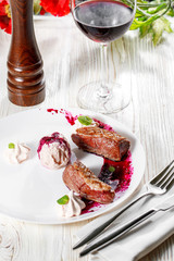 Duck breast with cherry pomegranate sauce on white plate. wooden background.