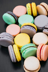 Colorful french macaroons or macarons on black wooden table. Space for text.