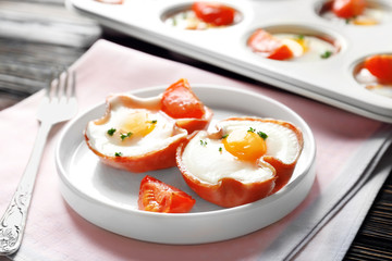 Plate with tasty eggs in ham on table