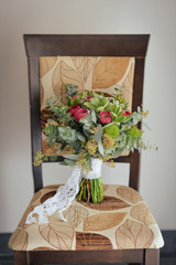 A bouquet of a burgundy color bride is on a chair